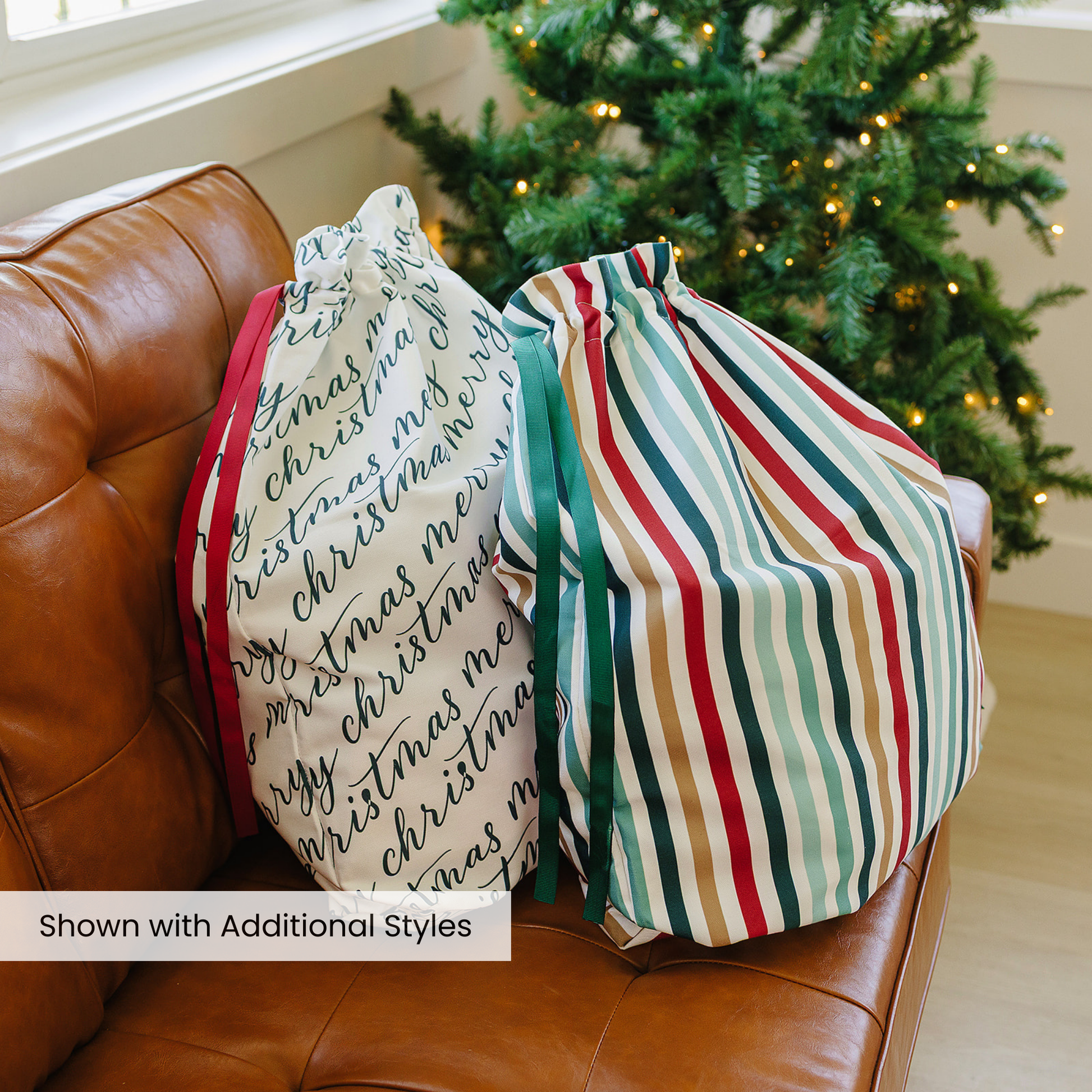 Two decorative pillows on a brown leather couch with a Christmas tree in the background.