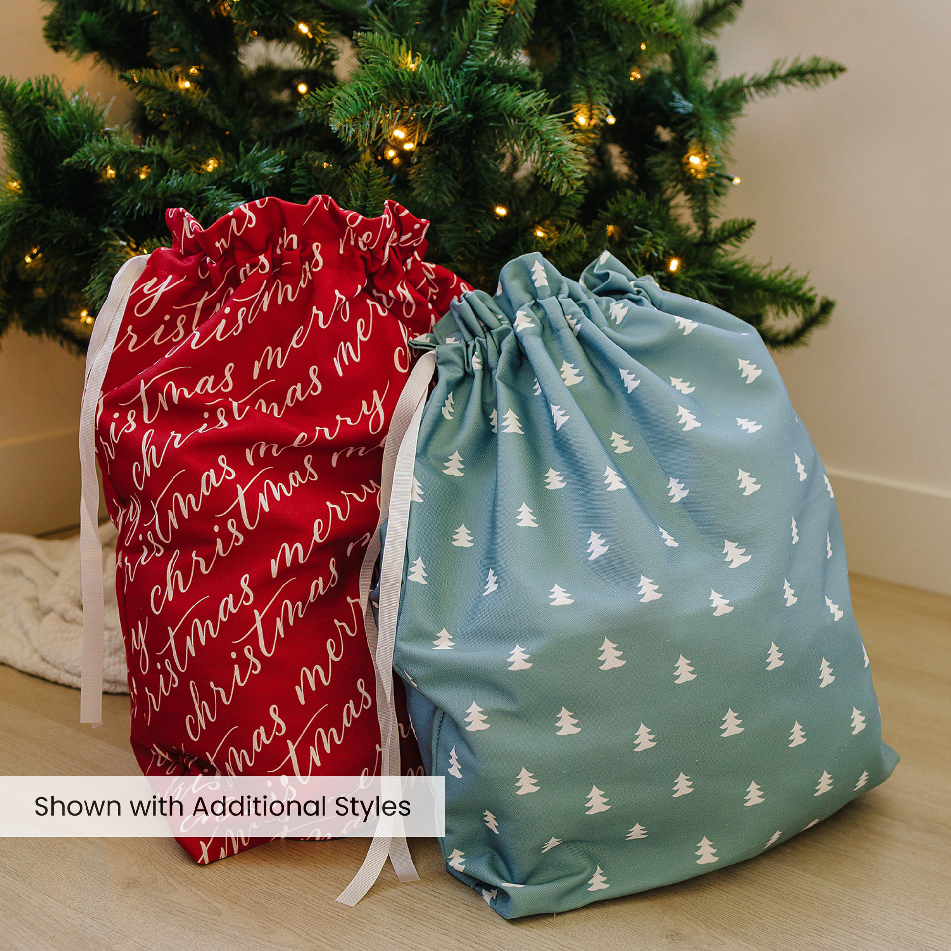Red and green drawstring bags with Christmas-themed designs in front of a decorated tree.