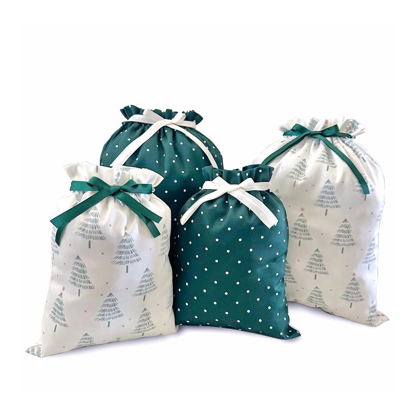Four fabric drawstring gift bags arranged together on a white background. Two bags are white with a gray Christmas tree print and tied with dark green ribbons, and two bags are dark green with white polka dots and tied with white ribbons.