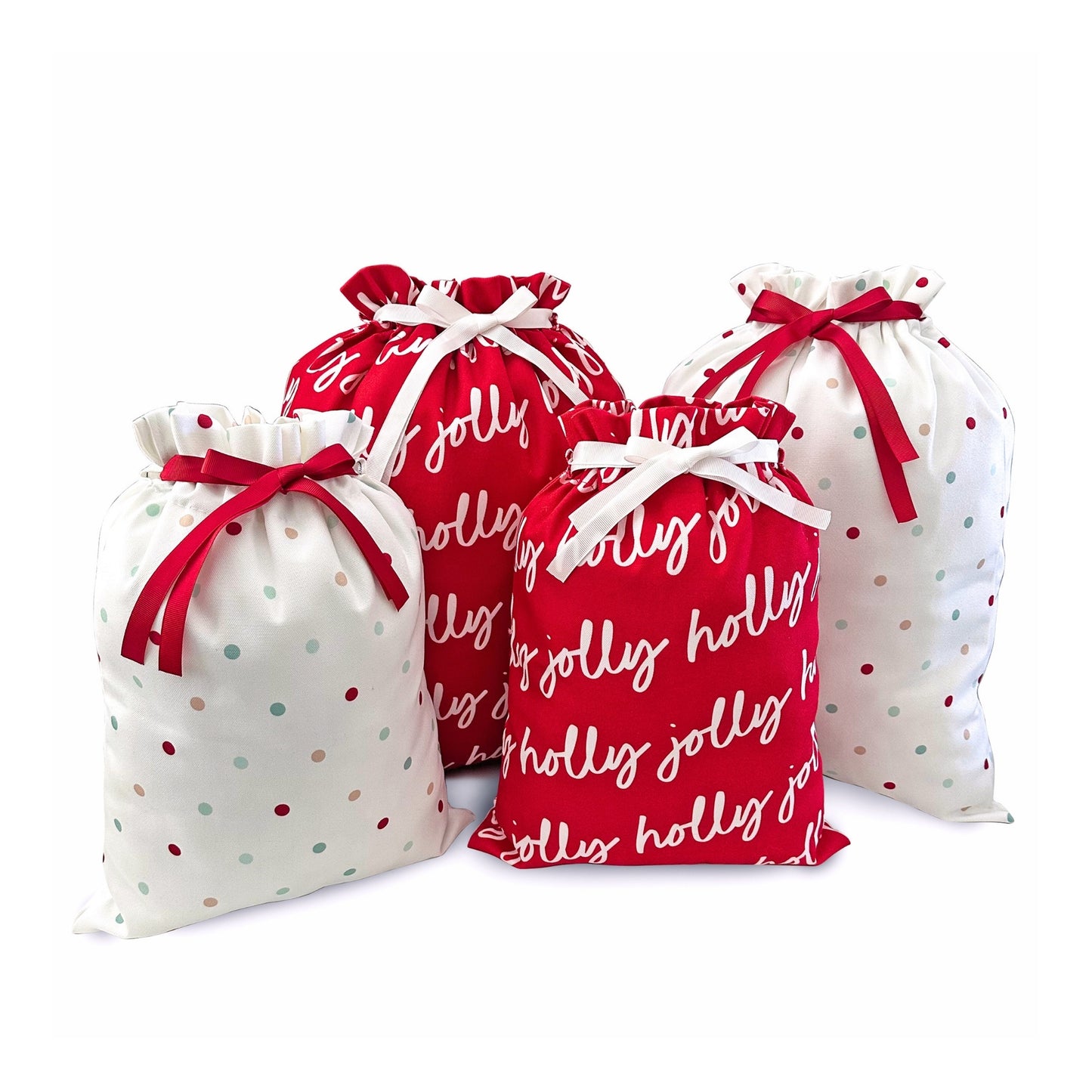 Four fabric drawstring gift bags arranged together on a white background. Two bags are red with white script text reading 'holly jolly' and white with small red and blue polka dots, while the other two are white with small red and blue polka dots and red script text.