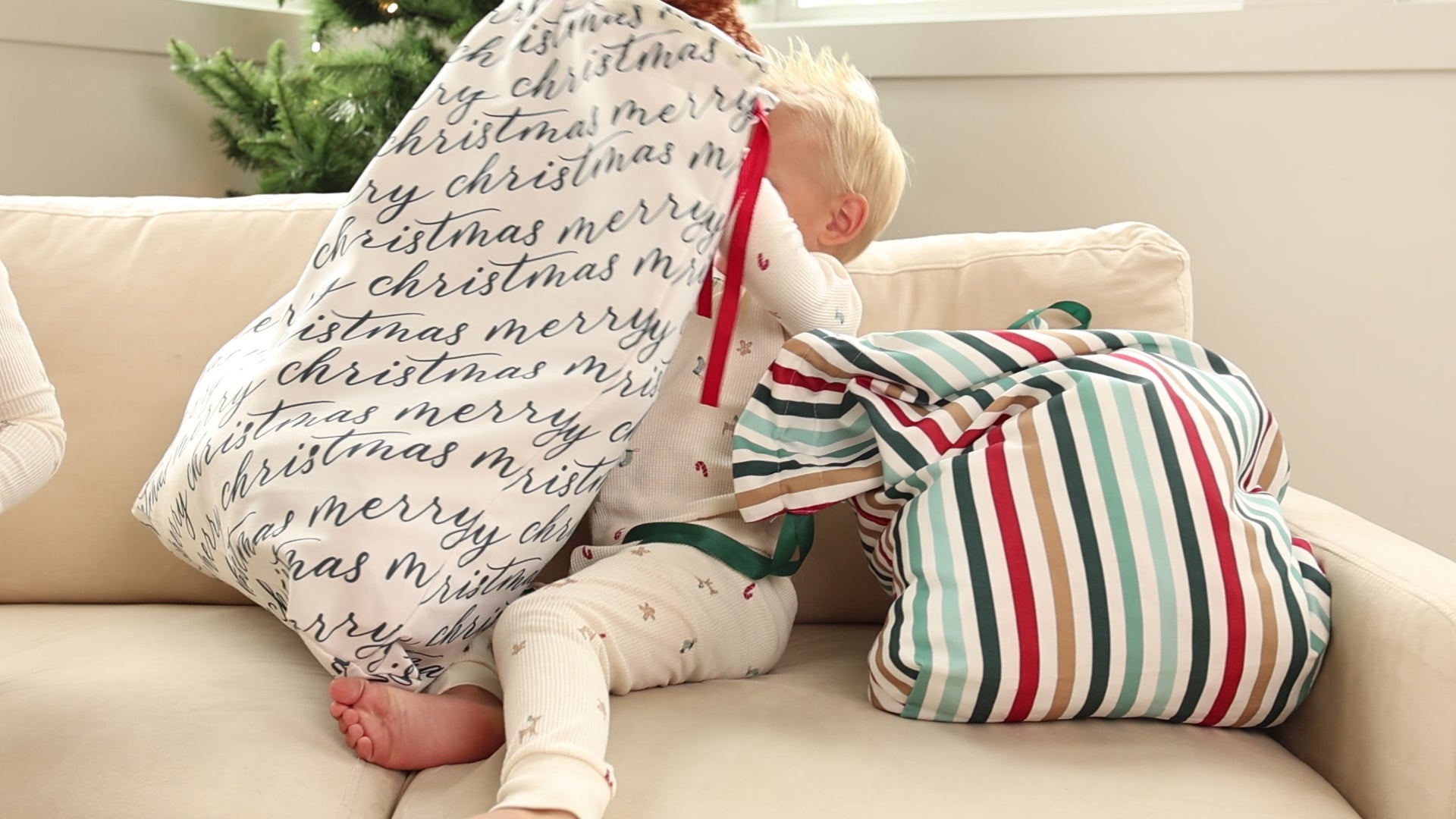 Two fabric gift bags with 'Merry Christmas' text in black calligraphy and stripes, each adorned with grosgrain ribbon.